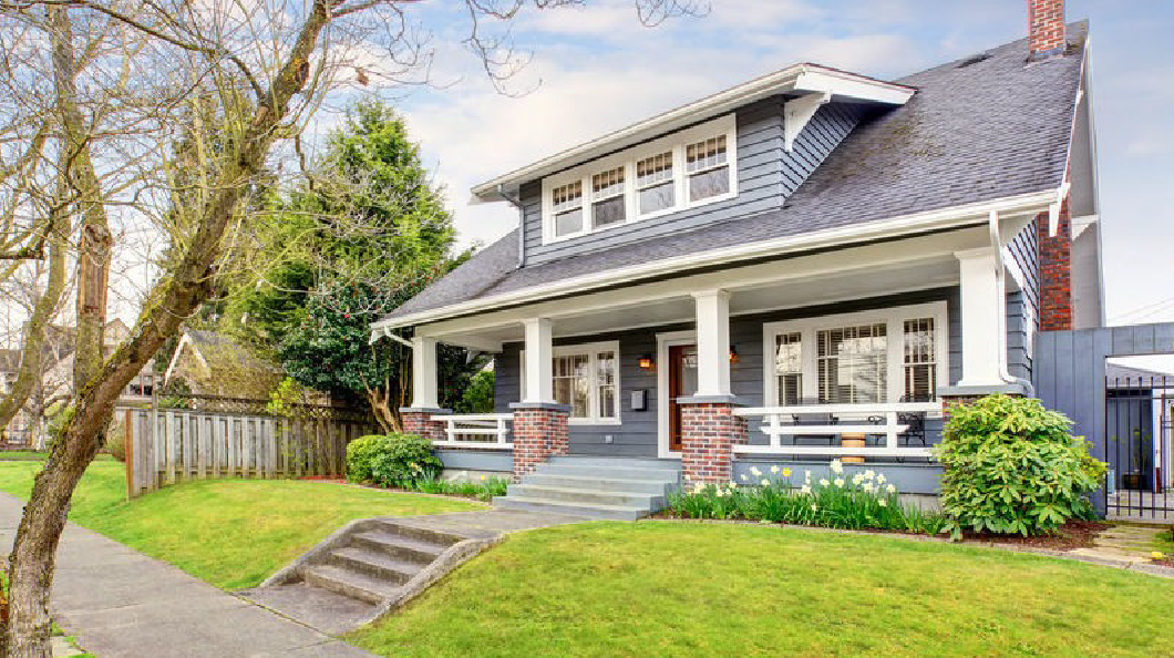 The house has a white and gray color scheme, and it is surrounded by trees